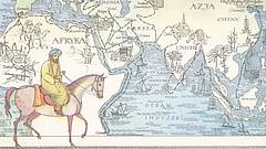 Der Entdecker Ibn Battuta auf einem Pferd und hinter ihm eine Karte über seine hinterlegten Reisen.